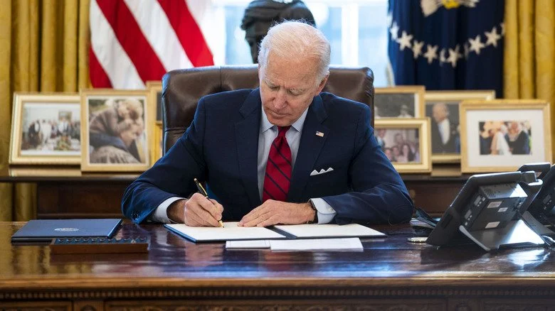 President Joe Biden signs a paper