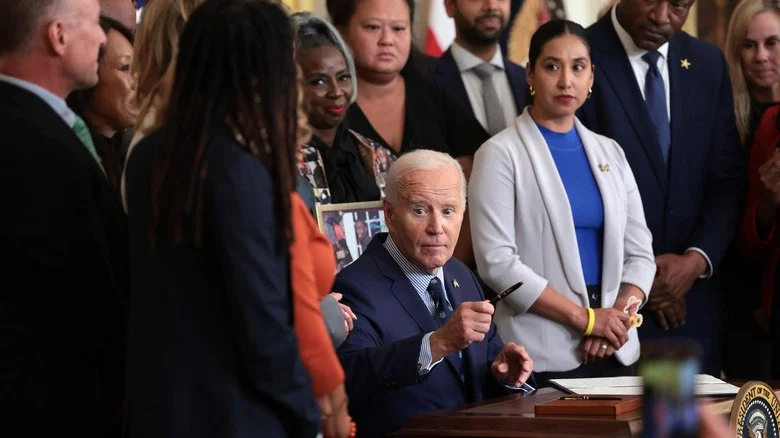 Joe Biden lève son stylo entouré de personnel