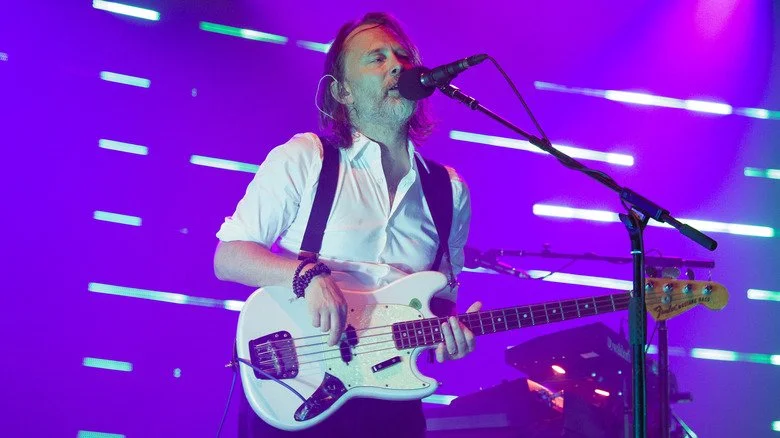 Thom Yorke chantant sur scène et jouant de la basse
