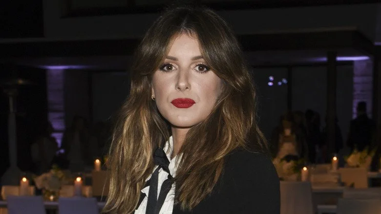 Shenae Grimes portant une chemise blanche et une veste noire posant pour une photo