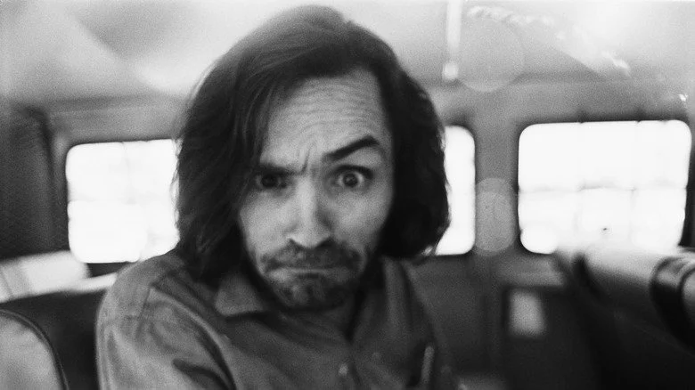 Charles Manson dans une voiture, levant le sourcil