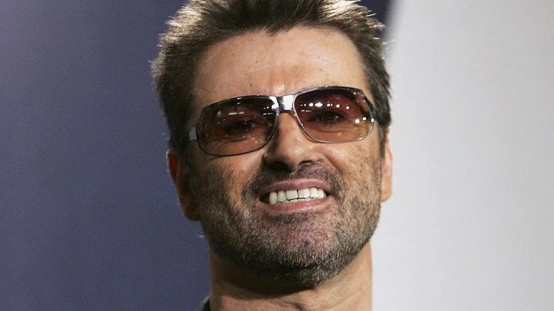 George Michael avec des lunettes de soleil souriant