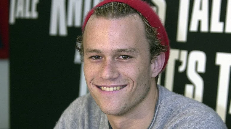 Heath Ledger avec un chapeau rouge souriant