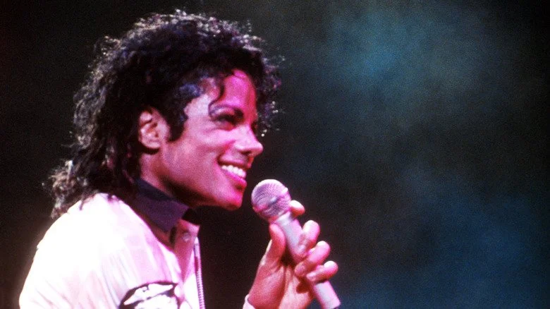 Michael Jackson souriant avec un microphone sur scène