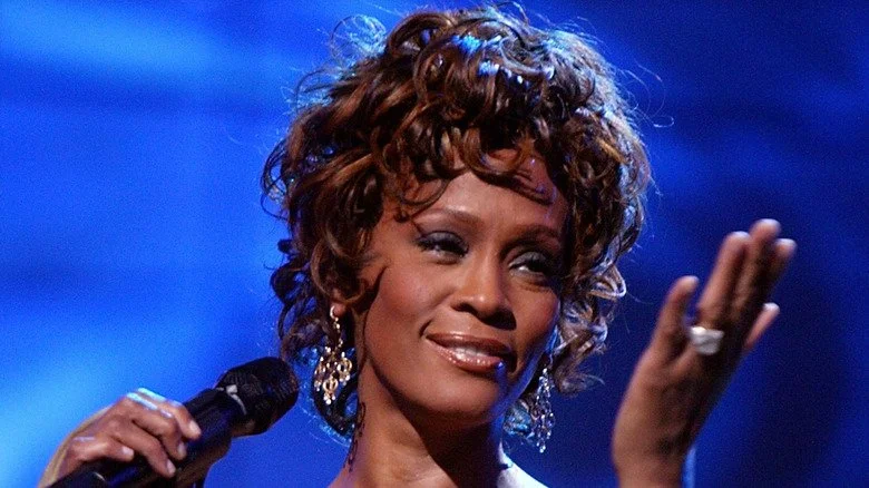 Whitney Houston chantant sur scène avec un geste de gratitude