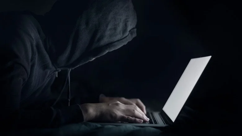 Figure encapuchonnée à l'ordinateur portable