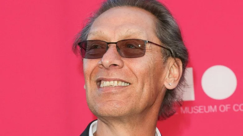 Alex Van Halen souriant avec des lunettes de soleil