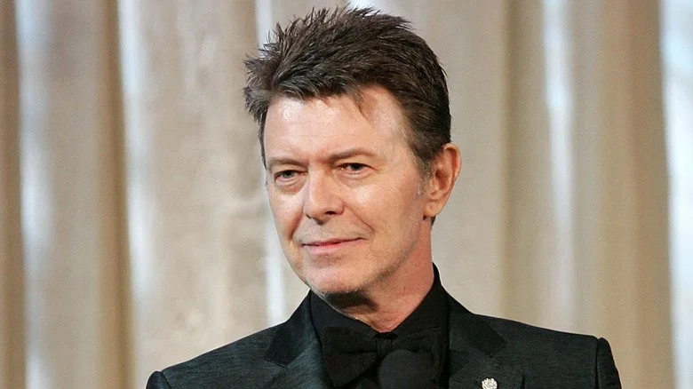 David Bowie souriant sur scène et regardant au loin