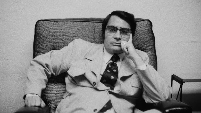 Jim Jones s'appuyant sur son coude dans une chaise