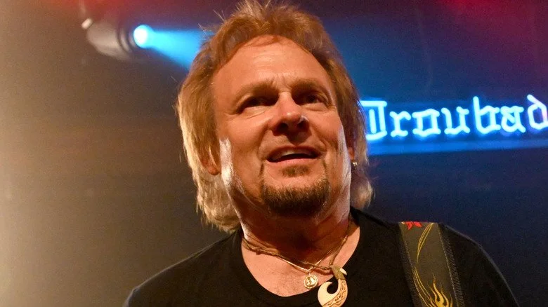 Michael Anthony jouant de la basse sur scène et faisant une grimace