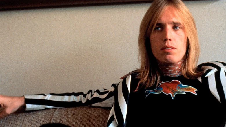 Tom Petty assis sur un canapé, regardant ailleurs