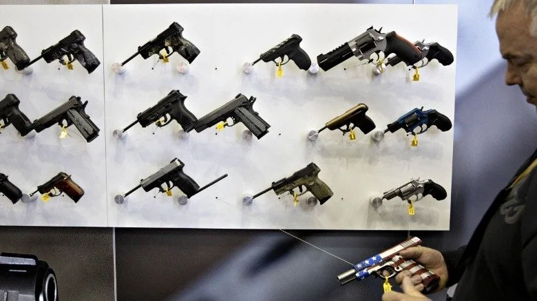 Homme examinant une pistolet Taurus avec le drapeau américain