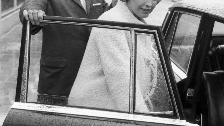 Homme tenant une portière de voiture pour une femme dans les années 1960