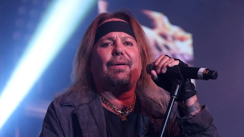 Vince Neil avec bandana sur scène tenant un micro