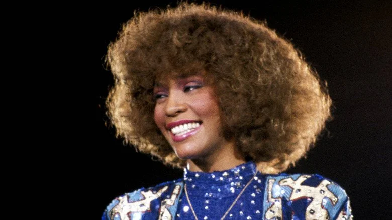 Whitney Houston avec de grandes cheveux dans les années 1980, regardant sur le côté