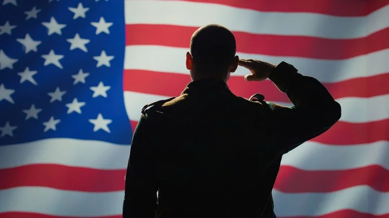 Military person saluting American flag