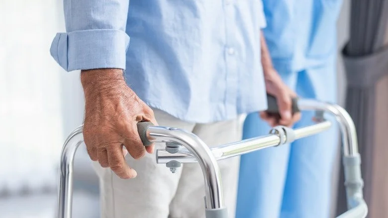 Personne avec déambulateur aidée par un soignant