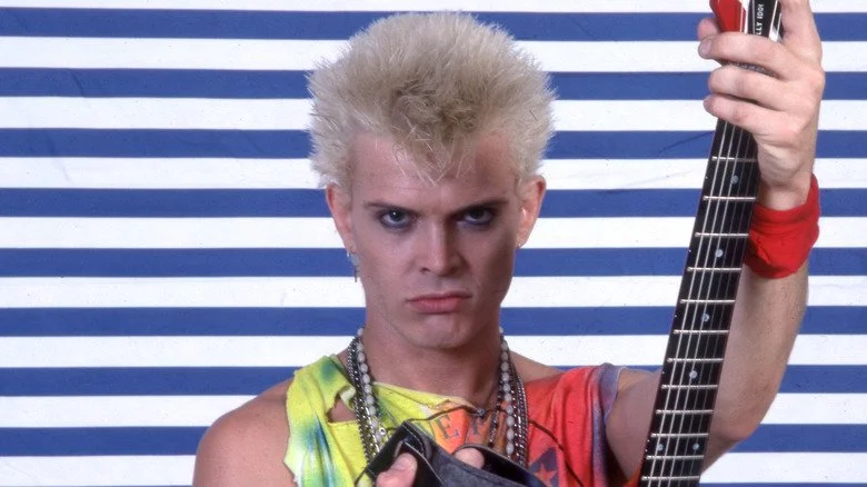 Billy Idol tenant une guitare et portant un débardeur tie-dye
