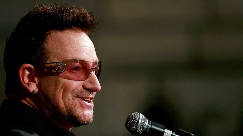 Bono souriant avec un micro