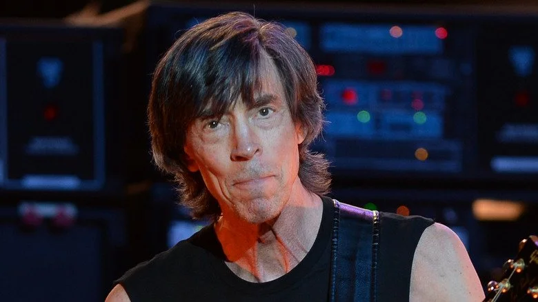 Tom Scholz joue de la guitare devant un équipement électrique