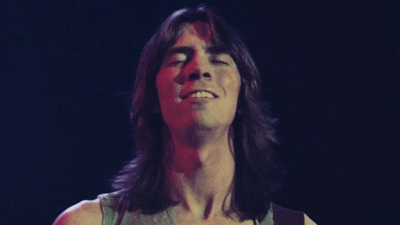 Tom Scholz joue de la guitare sur scène, les yeux fermés