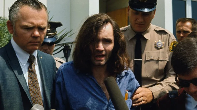 Charles Manson being interviewed leaving court with police