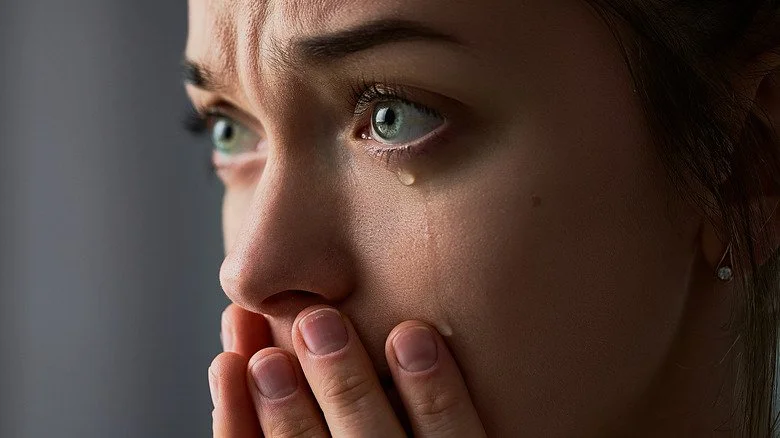 Une femme pleurant, les mains sur la bouche