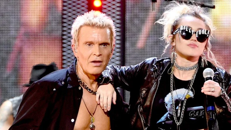 Miley Cyrus repose son bras sur Billy Idol sur scène