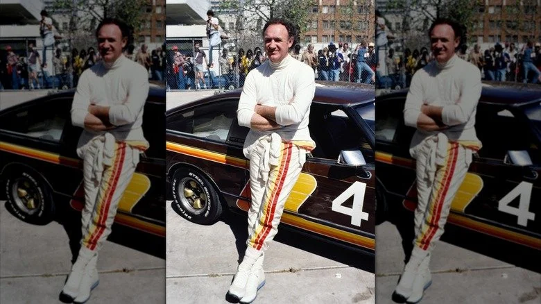 Gene Hackman posant devant une voiture de course