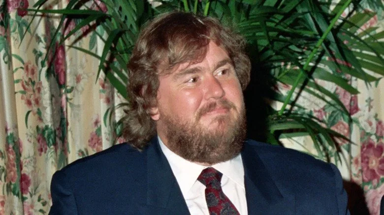John Candy avec une barbe portant un costume et une cravate