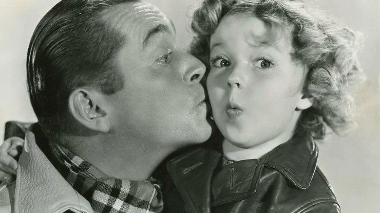 James Dunn donnant un baiser sur la joue de Shirley Temple, photo promotionnelle