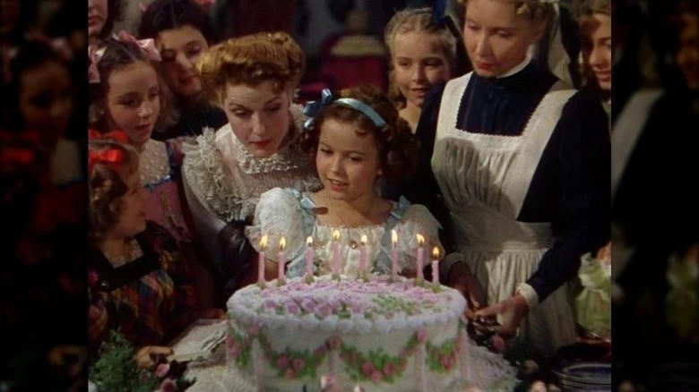 Shirley Temple assise devant un gâteau d'anniversaire
