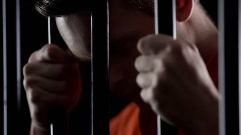 Homme derrière les barreaux d’une prison