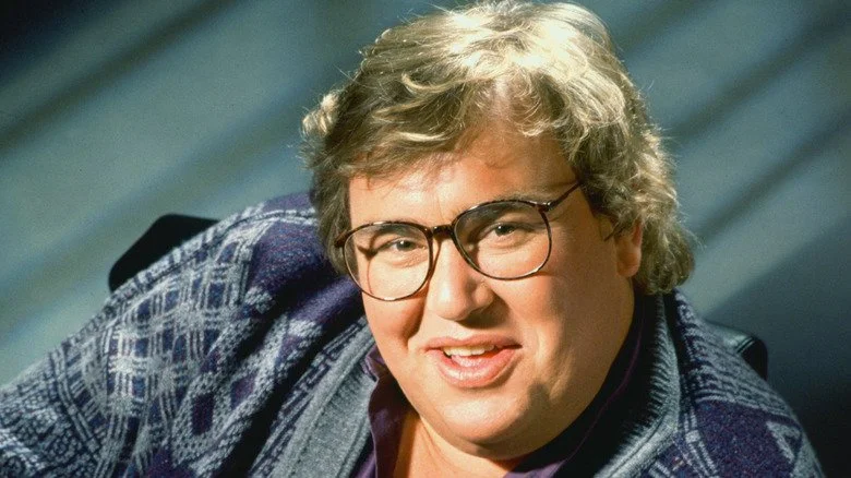 John Candy posant avec un pull en souriant en 1993