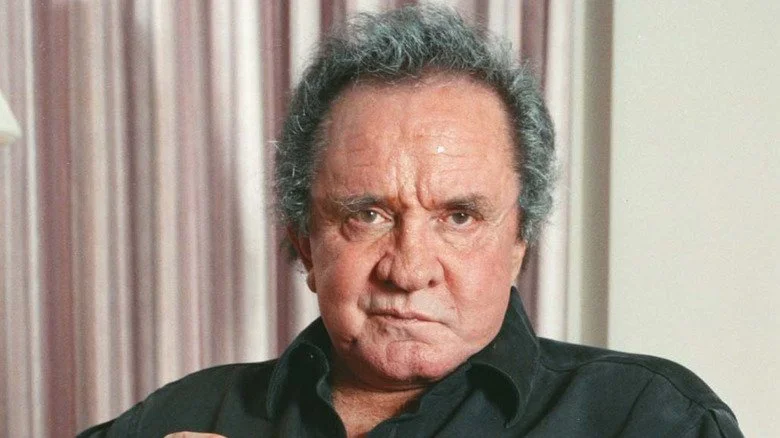 Johnny Cash with a sneer in front of curtains