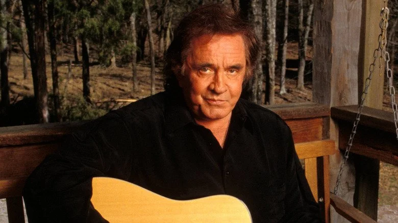 Johnny Cash jouant de la guitare sur une balançoire dans les bois