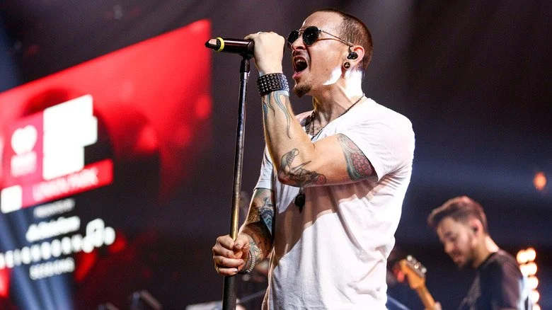 Chester Bennington portant des lunettes de soleil et se produisant sur scène avec Linkin Park