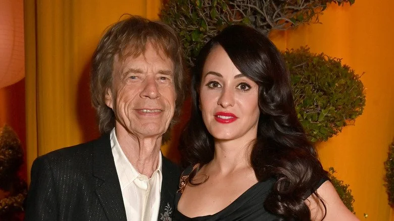 Mick Jagger souriant et se tenant près de la surprenante Melanie Hamrick