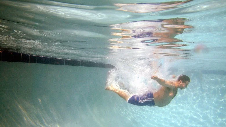 Homme se jetant à plat ventre dans une piscine