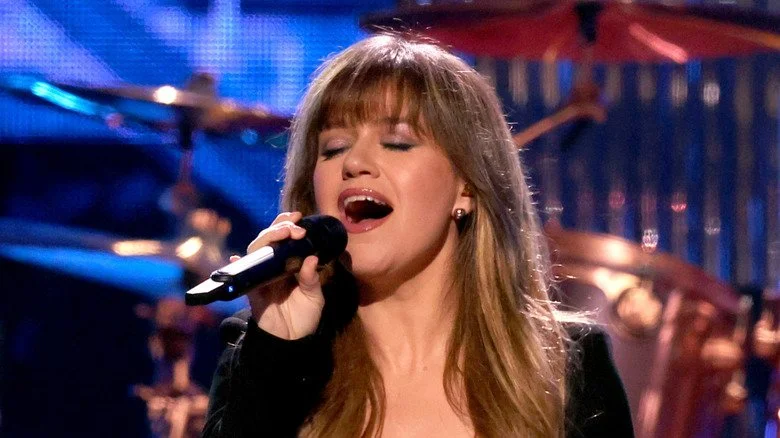 Kelly Clarkson chantant sur scène avec des batteries en arrière-plan