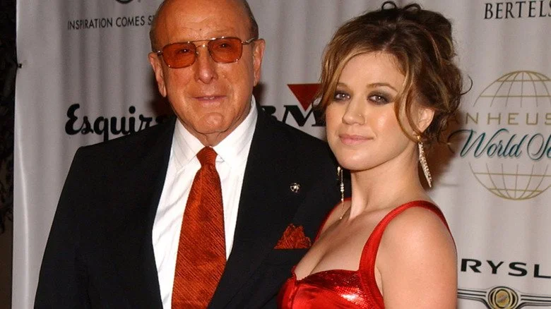 Clive Davis et Kelly Clarkson souriant en robe rouge lors d'un événement