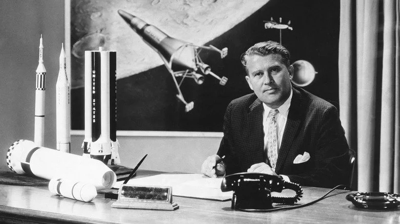 Wernher von Braun assis à son bureau avec des modèles de fusées NASA