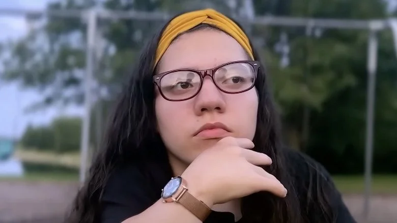 Natalia Grace avec des lunettes, la main sur le menton