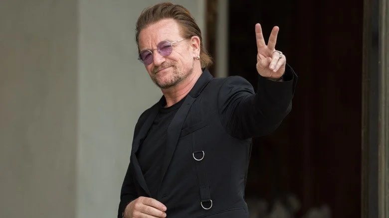Bono de U2 faisant un signe de paix à la caméra