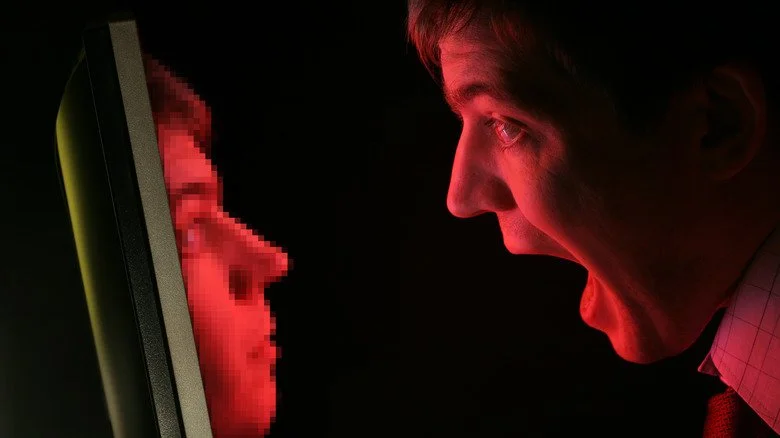 Homme avec la bouche ouverte regardant une version pixelisée de lui-même provenant d'un ordinateur