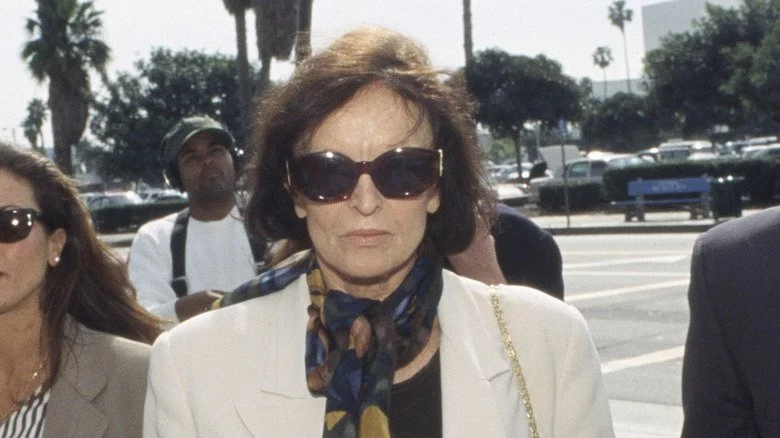 Judi Brown, mère de Nicole Brown Simpson, portant des lunettes de soleil et une écharpe.