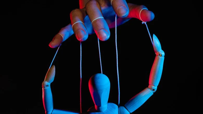 Main manipulant une figurine en bois