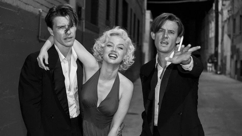 Ana de Armas playing Marilyn Monroe smiling with two men in Blonde