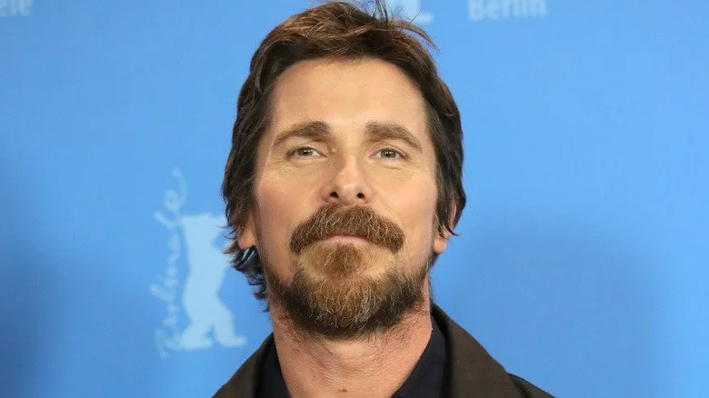 Christian Bale barbu devant un fond bleu