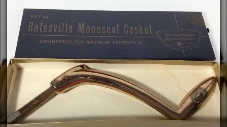 Une clé en laiton pour cercueil dans son écrin avec le couvercle ouvert